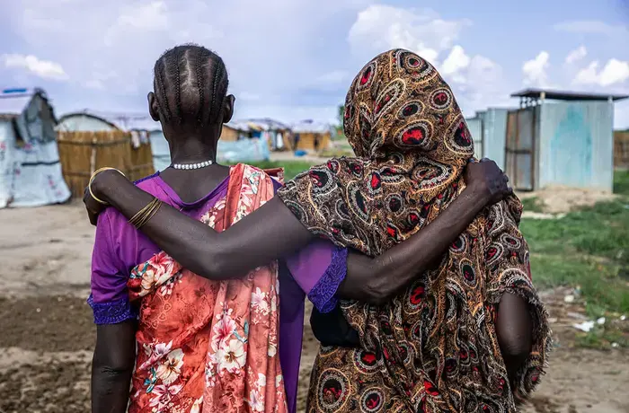 Women walk arm in arm in IDP [internally displaced persons] Site A, in Bentiu, South Sudan in 2023. Some of the women here have survived sexual violence. In this site, UNFPA, with the support of the CERF Fund, has set up a safe space for them, without men, so that they can recover and set up income-generating activities. Photo: OCHA/Alioune Ndiaye.
